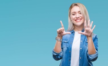 Genç Sarışın kadın gösterilen ve parmakları ile işaret izole arka plan yüzünden kendinden emin ve mutlu gülümseyerek süre yedi numara.