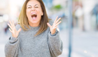 Arka plan deli kutluyor üzerinde kış kazak giyen güzel orta yaş kadın izole ve crazy arms ile başarı için kaldırdı ve heyecanlı çığlık gözler kapalı. Kazanan kavramı