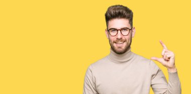 Gülümseyen bardakları ve boyutu işaret parmaklı ararken ve kamera işi el ile kendine güvenen el hareketi giyen genç yakışıklı iş adam. Ölçü kavramı.