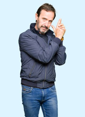 Orta yaş yakışıklı adam el hareketi ile sembolik silah tutan, çekim silah, kızgın yüz öldürmek oynamaya bir ceket