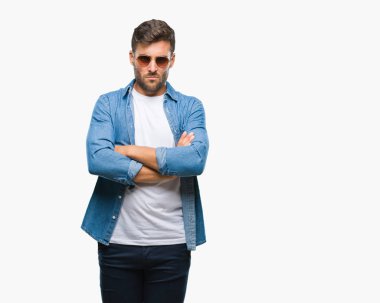 Genç yakışıklı adam izole arka plan şüpheci ve sinir, onaylamayan ifade yüz çapraz kolları üzerinde güneş gözlüğü takıyor. Negatif kişi.