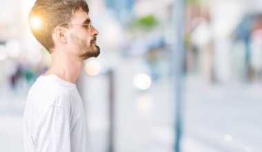 Genç yakışıklı adam giyen güneş gözlüğü izole arka tarafına, seyir üzerinde dinlenmek doğal yüz emin gülümseme ile pozuyla profili.