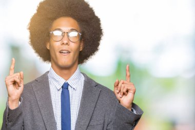 Afro saçlı gözlüklü genç Afro-Amerikalı iş adamı hayrete ve yukarıya bakıyor ve parmakları ile işaret ve silah kaldırdı şaşırttı.