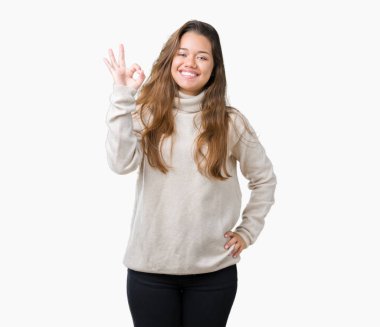 İzole arka plan el ve parmaklar ok işaretiyle yapıyor olumlu gülümseyen üzerinde boğazlı kazak giyen genç güzel esmer kadın. Başarılı ifade.