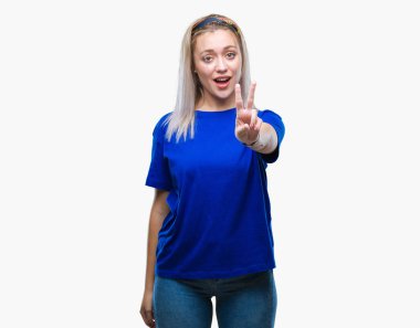 Genç Sarışın kadın mutlu yüz zafer işareti yaparken kameraya göz kırpıyor ile gülümseyen izole arka plan yüzünden. İki numaralı.