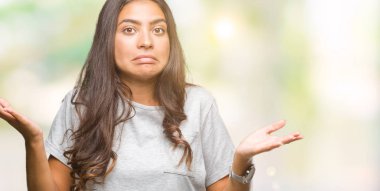 Genç güzel Arap kadın izole arka plan clueless ve şaşkın bir ifadeyle kollar ve eller kaldırdı. Şüphe kavramı.