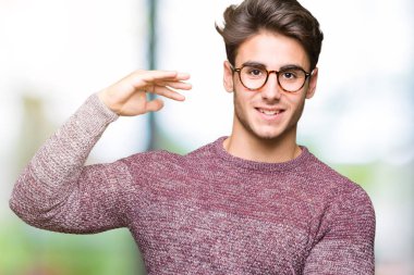 Büyük ve büyük boy işaret, ölçü birimi sembol gösteren ellerle eller izole arka plan üzerinde gözlük takan yakışıklı delikanlı. Kameraya bakarak gülümsüyordu. Ölçüm kavramı.