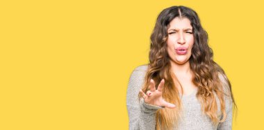 Kış elbise giyen genç güzel kadın tiksinti ifadesi, memnun ve korkulu tiksinti yüz yapıyorsun çünkü nefret tepki. Elleriyle kaldırdı. Sinir bozucu kavramı.