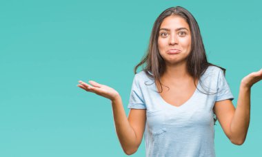 Genç güzel Arap kadın izole arka plan clueless ve şaşkın bir ifadeyle kollar ve eller kaldırdı. Şüphe kavramı.