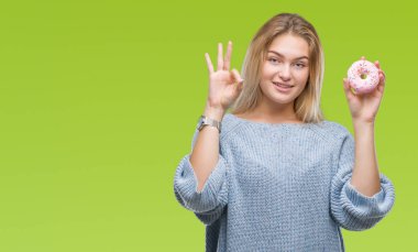 Parmak, mükemmel sembolü ile ok işareti yapıyor izole arka plan üzerinde tatlı çörek yiyen genç kafkas kadın