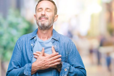 Orta yaş ağarmış komuta sizde ile gülümseyen izole arka plan üzerinde kapalı gözler ve yüzünde minnettar jest ile göğüs üzerinde eller. Sağlık kavramı.