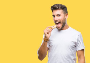 Yakışıklı delikanlı acımak yüz ciddi düşünüyorum üstünde kendine güvenen bir ifade ile izole arka plan üzerinde çikolata çerez yemek