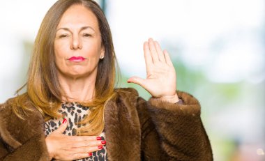 Güzel orta yaş zarif kadın giyiyor vizon ceket Swearing göğüs ve avuç el ile bir sadakat sözü yemin yapımı