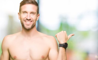 Gömleksiz yakışıklı gösteren çıplak göğüs seyir ve başparmak yanında yukarıyı mutlu yüz ile gülümseyen.