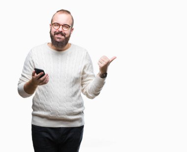Genç beyaz hipster adam manifatura işaret ve başparmak kadar mutlu yüz gülümseyen tarafı ile gösteren izole arka plan üzerinde Smartphone kullanarak ileti gönderme