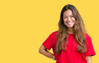 Yüzünde mutlu ve güzel bir gülümseme ile izole arka plan üzerinde kırmızı t-shirt giyen genç güzel esmer kadın. Şanslı kişi.