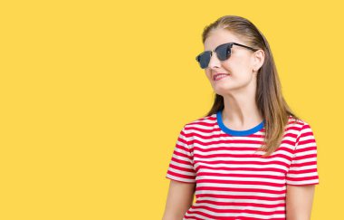 Orta yaş Olgun kadın üzerinde güneş gözlüğü takıyor arka plan uzak tarafına gülümseme ile yüzünde, doğal ifade arıyorum izole. Kendine güvenen gülüyor.