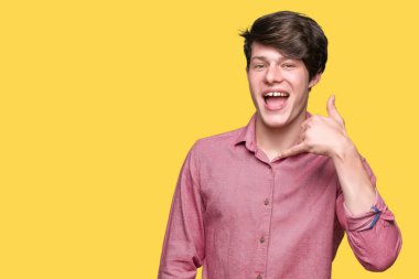 Genç yakışıklı iş adamı yapıyor gülümseyen izole arka plan üzerinde telefon hareketi ile el ve parmak telefonda konuşuyor gibi. Kavramları iletişim.