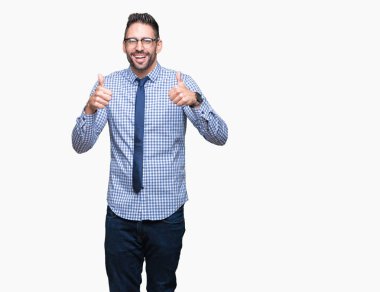 El ile pozitif jest yapıyor izole arka plan başarı işareti üzerinde gözlük takan genç iş adamı başparmak gülümseyen ve mutlu. Neşeli bir ifadeyle, kazanan jest kameraya bakıyor.