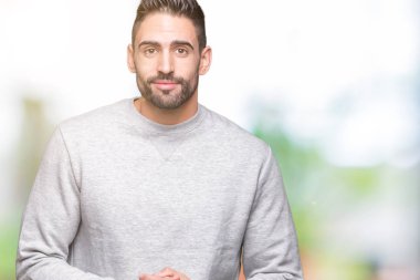 Üzerine tişört giyen genç yakışıklı adam arka plan eller birlikte izole ve rahat ve neşeli gülümseyen parmak çarpı işareti. Başarı ve iyimser