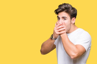 Üzerinde beyaz t-shirt giyen genç yakışıklı adam arka plan ağız hata için elleriyle kapsayan şok izole. Gizli kavramı.
