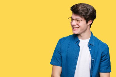 Uzak tarafına yüzünde, doğal ifade gülümseme ile seyir izole arka plan üzerinde gözlük takan yakışıklı delikanlı. Kendine güvenen gülüyor.