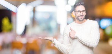 İzole arka plan gösteren palm el üzerinde gözlük takan ve yukarıya, mutlu ve neşeli gülümseyen baş parmakları Tamam jest yapıyor yakışıklı delikanlı