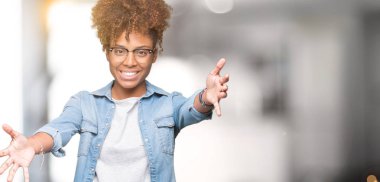 Sarılmak için kollarını açarak gülümseyerek kameraya bakarak izole arka plan üzerinde gözlük güzel genç Afro-Amerikan kadın. Neşeli ifade kucaklayan mutluluk.