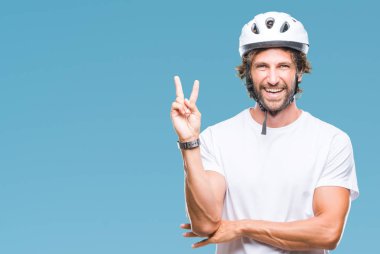 Mutlu yüz zafer işareti yaparken kameraya göz kırpıyor ile gülümseyen izole arka plan üzerinde güvenlik kask giyen yakışıklı İspanyol bisikletçi adam. İki numaralı.