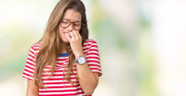 Genç güzel esmer kadın gözlük ve çizgili t-shirt stresli ve gergin ağız ısırma el ile izole arka plan üzerine çivi. Anksiyete sorunu.