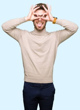 Dilini, parmaklarının arasından baktığını yapışmasını dürbün gibi ok jest yapıyor gözlüklü genç yakışıklı iş adamı. Deli ifade.