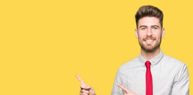 Gülümseyen ve iki elleri ve parmakları ile tarafına işaret kamera bakarak genç yakışıklı iş adamı.