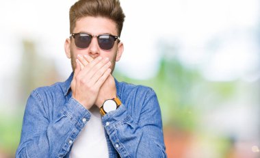 Denim ceket ağız hata için elleriyle kapsayan şok giyen genç yakışıklı zarif adam. Gizli kavramı.