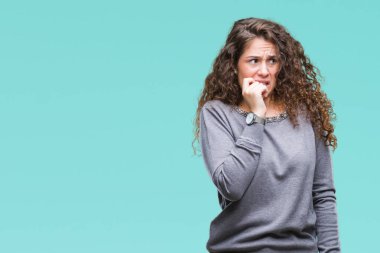 Güzel esmer kıvırcık saçlı Genç kız stresli ve gergin elle çivi ısırma ağzına bakarak izole arka plan üzerinde bir kazak giyiyor. Anksiyete sorunu.