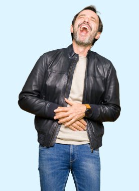 Siyah deri giyen orta yaş yakışıklı adam ceket gülen ve komik deli şaka çünkü yüksek sesle zor gülüyor. Mutlu ifade.