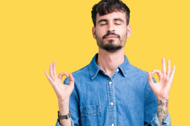 Yakışıklı delikanlı izole arka plan üzerinde dinlenmek ve gülümseyen gözlerle parmak ile meditasyon jest yapıyor kapalı. Yoga kavramı.