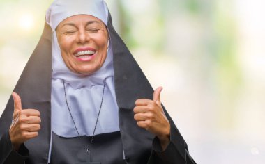 Orta yaş üst düzey Hıristiyan Katolik Rahibe kadın izole arka plan başarı işareti başparmak gülümseyen ve mutlu el ile olumlu hareketi yapıyor. Neşeli bir ifadeyle, kazanan jest kameraya bakıyor.