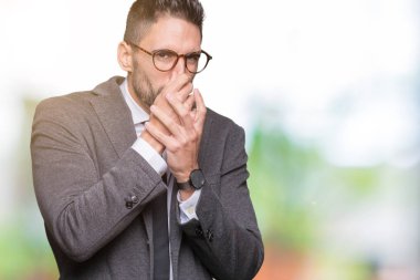 Genç yakışıklı iş adamı izole arka plan bir şey pis ve iğrenç kokulu, dayanılmaz koku, holding nefes burun parmaklar ile. Kötü kokuyor kavramı.