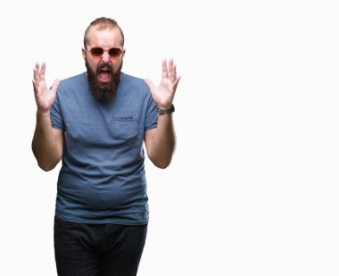 Üzerinde güneş gözlüğü takmış Genç beyaz hipster adam arka plan deli izole ve deli bağırarak ve agresif ifade ve silah kaldırdı bağırıyor. Hayal kırıklığı kavramı.