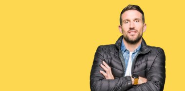 Kış ceket ile mutlu yüz gülümseyen giyen yakışıklı adam kameraya seyir silah geçti. Olumlu bir kişi.