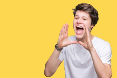 Kızgın ile yüksek sesle bağırarak izole arka plan üzerinde rahat beyaz t-shirt giyen genç yakışıklı adam ağzına eller