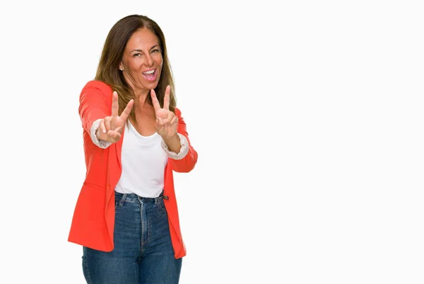勝利のサインをやって指を表示するカメラを笑みを浮かべて孤立の背景に美しい中年ビジネス大人の女性 — ストック写真