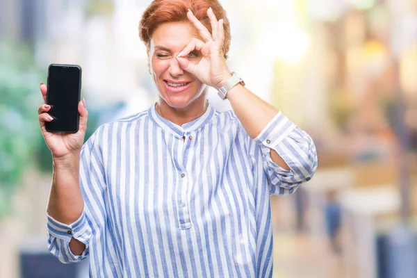 Attraktive Ältere Kaukasische Rothaarige Frau Zeigt Smartphone Bildschirm Über Isoliertem — Stockfoto