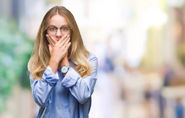 若い美しい金髪のビジネス女性が眼鏡をかけてミスのため手で口を覆っているショックを受けて孤立の背景の上 秘密の概念 — ストック写真