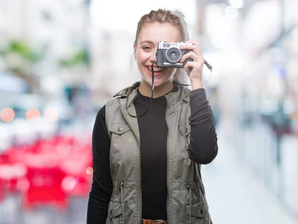年轻的金发碧眼的女人在孤立的背景下用老式相机拍照 一张幸福的脸站着 面带微笑 露出自信的笑容 露出牙齿 — 图库照片