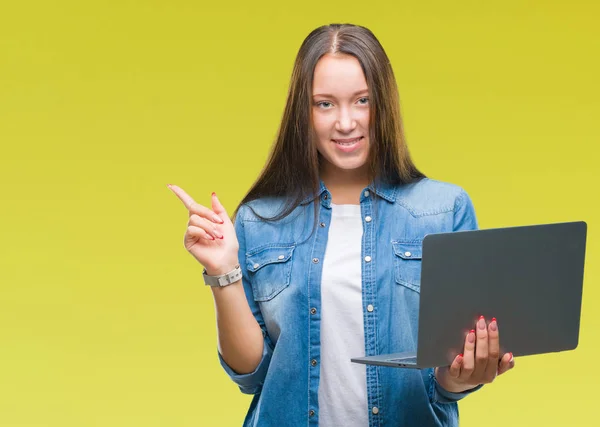 年轻的高加索妇女使用笔记本电脑在孤立的背景非常高兴用手和手指指向一边 — 图库照片