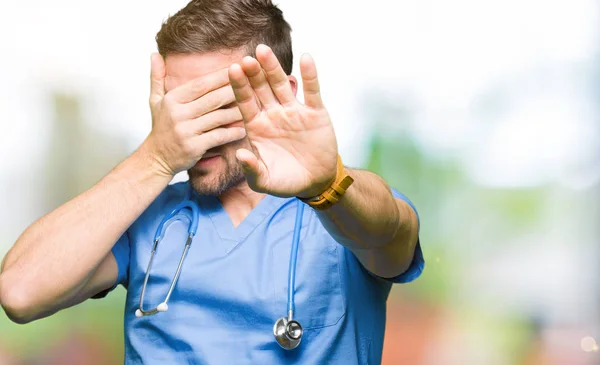 英俊的医生穿医疗制服在孤立的背景覆盖眼睛用手和做停止手势与悲伤和恐惧的表情 尴尬和消极的概念 — 图库照片