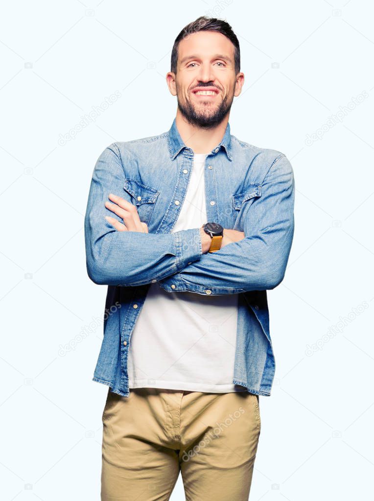 Handsome man with blue eyes and beard wearing denim jacket happy face smiling with crossed arms looking at the camera. Positive person.
