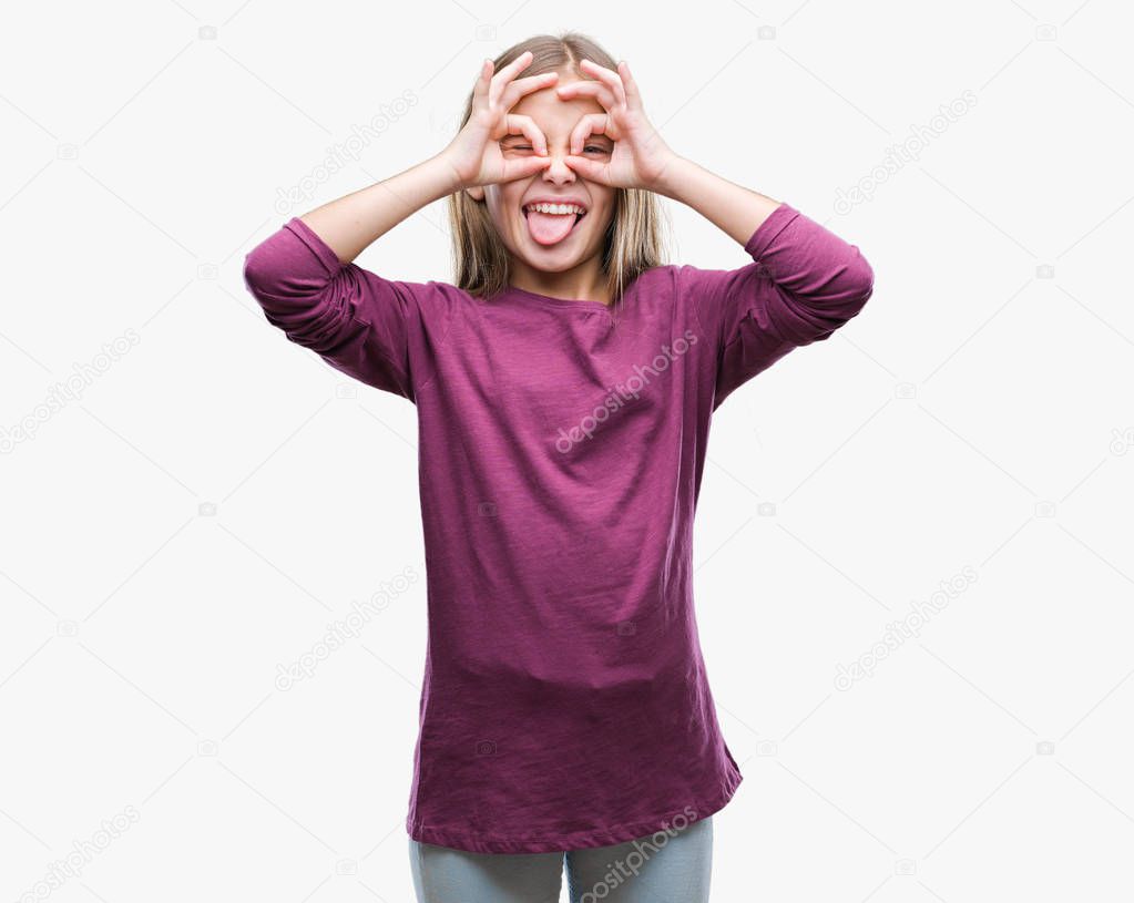 Young beautiful girl over isolated background doing ok gesture like binoculars sticking tongue out, eyes looking through fingers. Crazy expression.