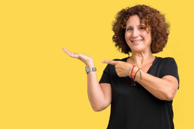 Hayret ve el ile sunulması ve parmak ile işaret ederken kameraya gülümseyen izole arka plan güzel orta ager üst düzey kadın.